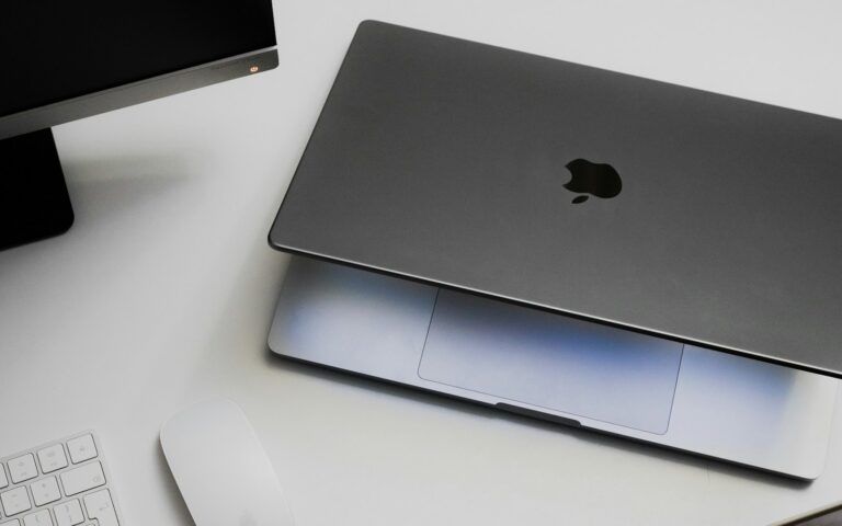 외부 모니터와 키보드, 마우스 옆에 닫힌 MacBook이 놓인 작업 공간